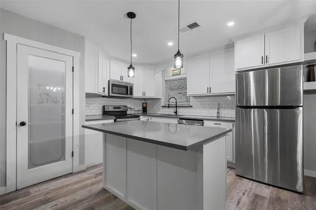 a kitchen with refrigerator a sink and a stove with wooden floor