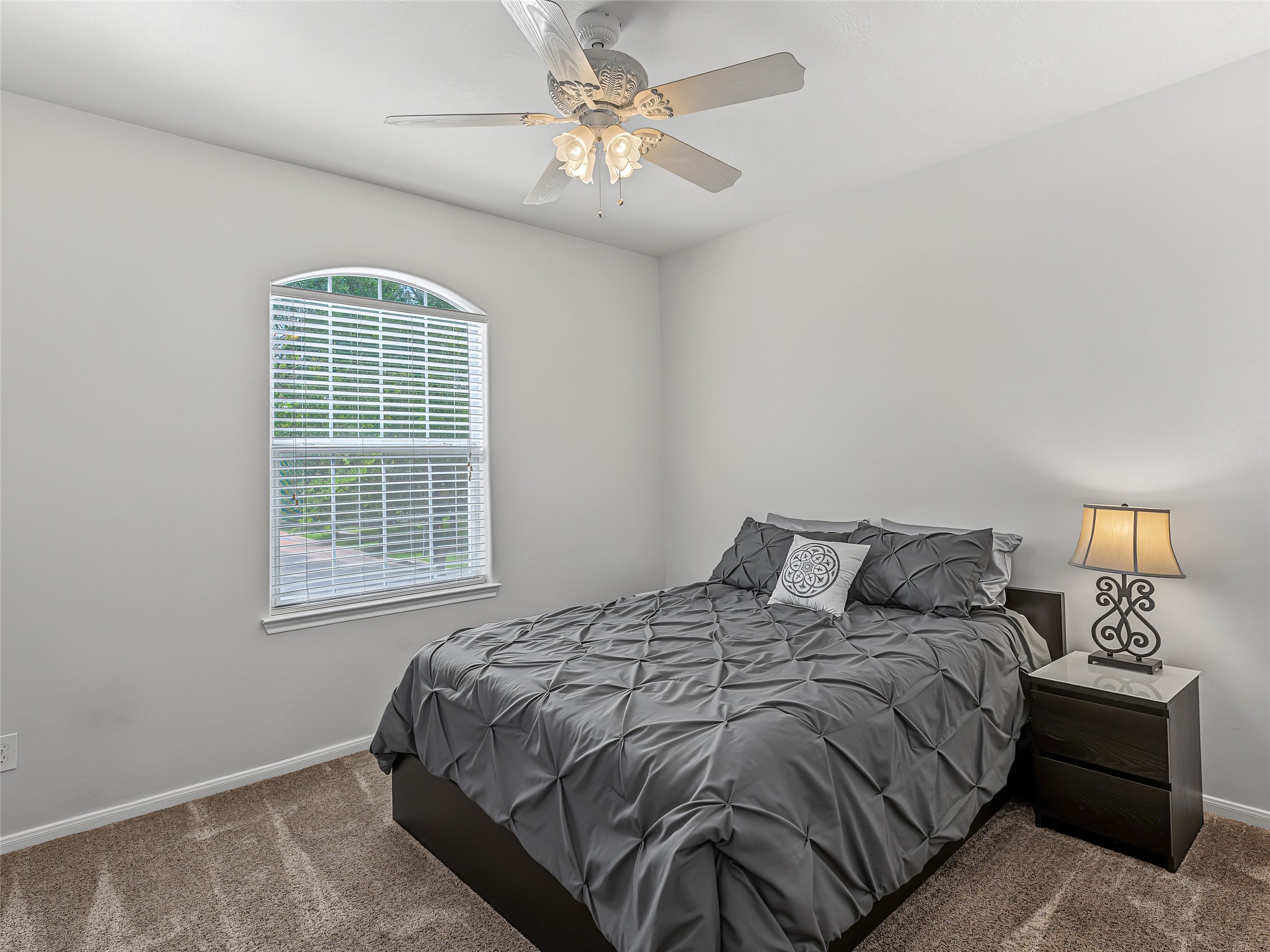 2210 Fox Path Katy, TX 77494 - Photo 32 of 47 Perfect for family or guests, this peaceful upstairs bedroom features a decorative white ceiling fan and a beautiful arched focal window that pours in soft, natural light with integrated blinds for easy privacy.