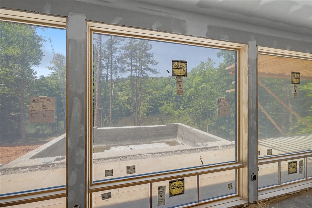 166 Ellenburg Creek Road Sunset, SC 29685 - Photo 16 of 20 Framed windows offer verdant forest views and a glimpse of the in-ground pool construction.