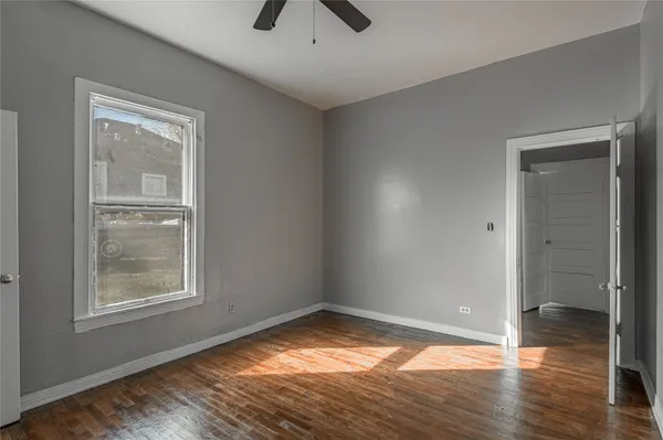a view of empty room with wooden floor and fan