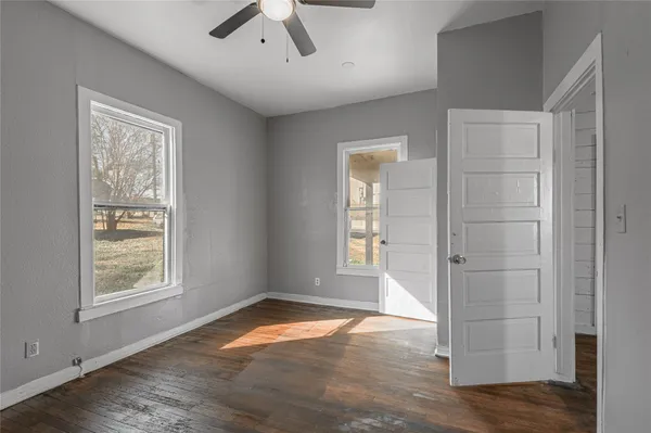 a view of empty room with wooden floor and fan
