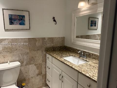 4716 Southwest 67th Avenue, Unit D2 Miami, FL 33155 - Photo 7 of 10 a bathroom with a granite countertop sink a toilet and a mirror