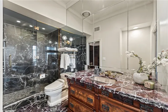 a bathroom with a granite countertop sink a toilet and shower