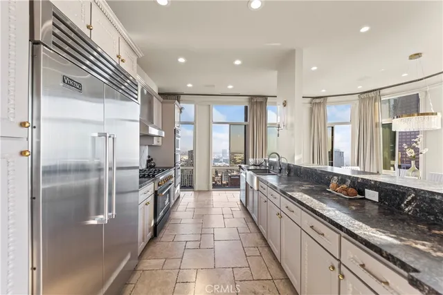 a large kitchen with a large counter top a sink stainless steel appliances and cabinets