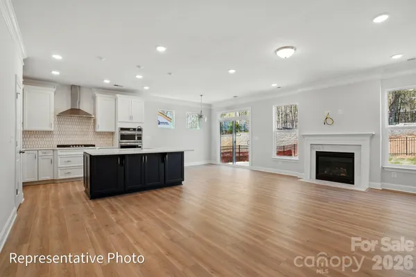 a large kitchen with stainless steel appliances granite countertop a large counter top a wooden floors and a large window