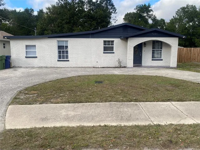 a view of a white house with large yard and large tree