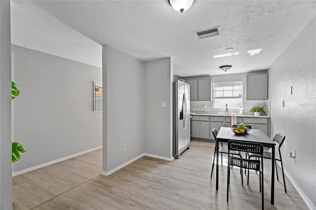 a kitchen with stainless steel appliances granite countertop a refrigerator a stove a sink a microwave a dining table and chairs with wooden floor