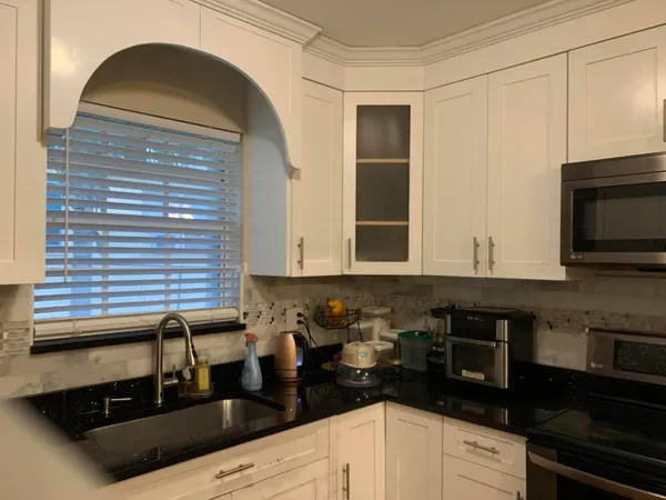 a kitchen with granite countertop a sink a stove and cabinets