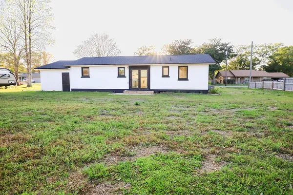 a view of a yard in front of a house with plants and large tree