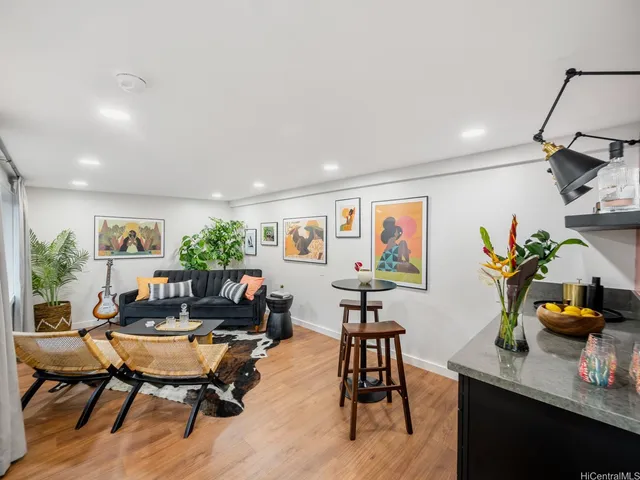 a living room with furniture kitchen view and a potted plant