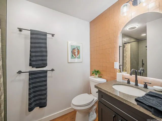a bathroom with a granite countertop toilet sink and mirror
