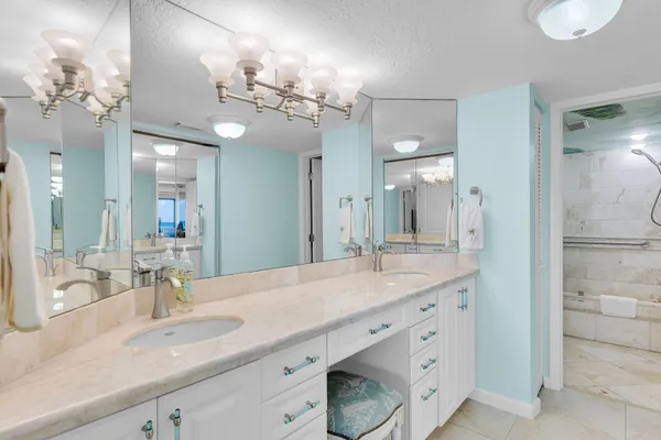 a bathroom with a granite countertop double vanity sink a mirror and shower
