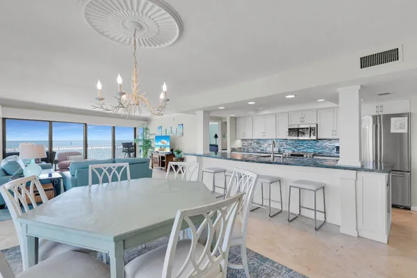 a kitchen with stainless steel appliances kitchen island granite countertop a dining table chairs and white cabinets
