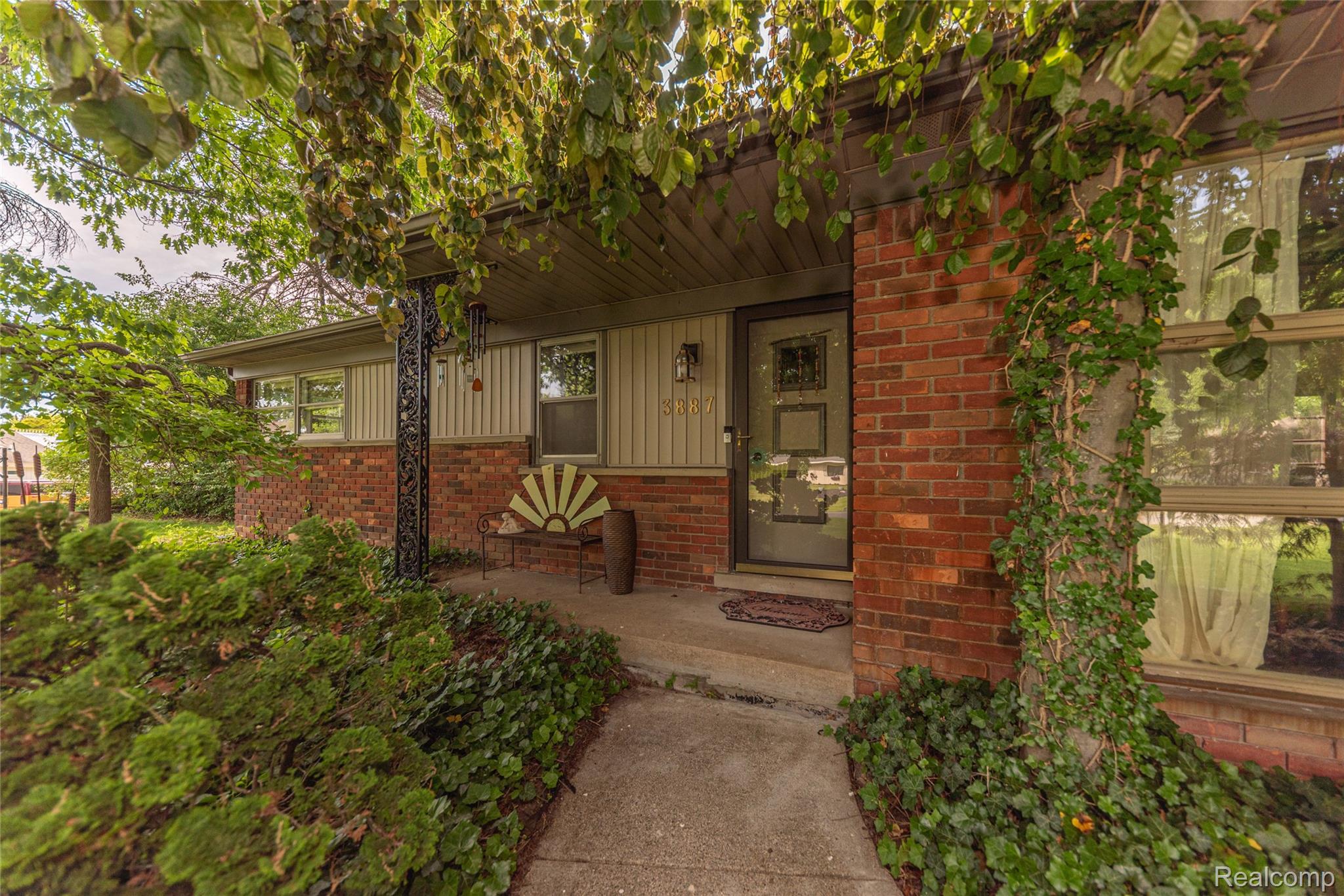 3887 Stonecrest Road West Bloomfield, MI 48322 - Photo 25 of 45 Front facade featuring brick and siding construction, covered entry with decorative metal support column, front door with decorative glass inserts, and established landscaping