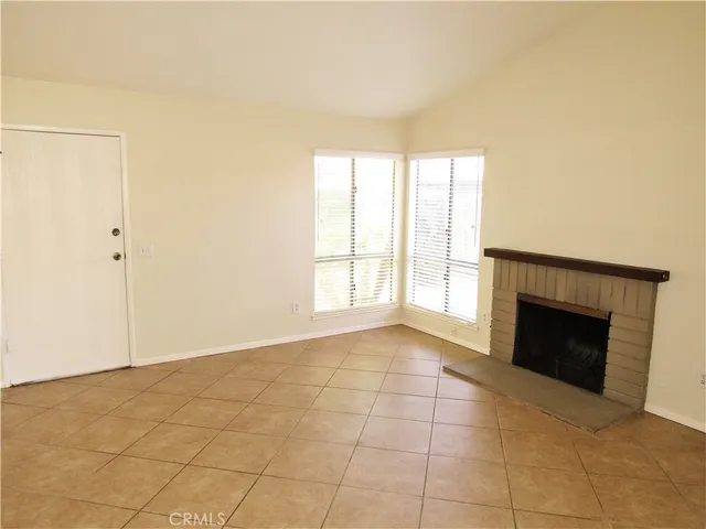 a view of an empty room with a fireplace and a window