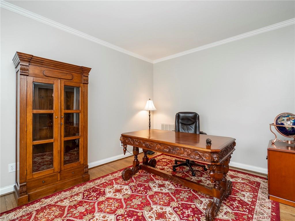 2811 Norwell Court Oak Ridge, NC 27310 - Photo 11 of 50 Spacious formal living room with plenty of room for a large desk, filing cabinet, bookcases and a seating area, if desired, hardwood floors, neutral paint colors and crown molding.