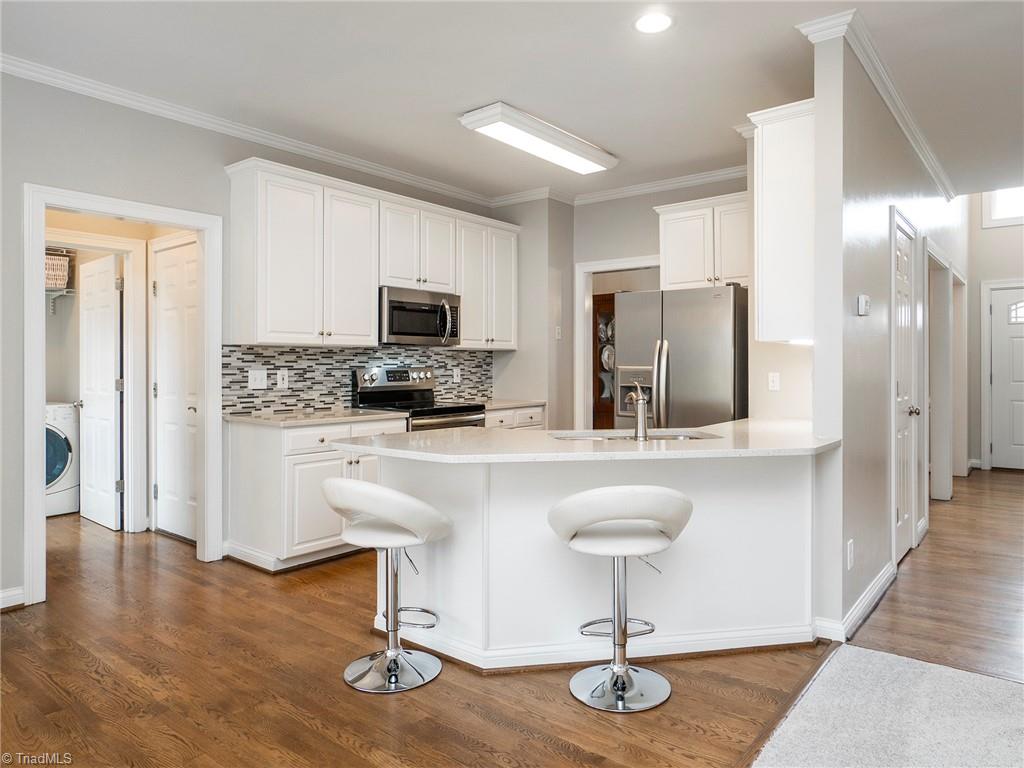 2811 Norwell Court Oak Ridge, NC 27310 - Photo 14 of 50 Kitchen offers bar seating, recessed lighting, quartz counter tops, all stainless steel appliances, and is open to family room.
