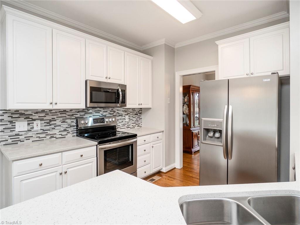 2811 Norwell Court Oak Ridge, NC 27310 - Photo 5 of 50 Enjoy the newly renovated kitchen with sparkling quartz countertops, custom glass tiling and all stainless-steel appliances.