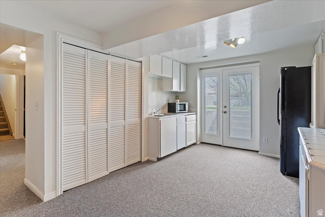 5321 South 3100th Street West Roy, UT 84067 - Photo 47 of 64 Carpeted room featuring louvered bi-fold closet doors, white cabinetry, a single-basin sink, and double glass-paneled patio doors