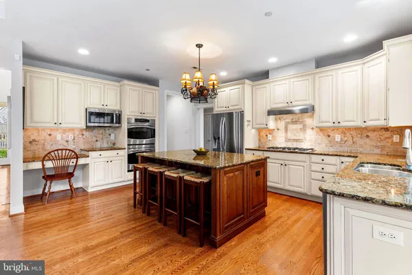 a kitchen with kitchen island granite countertop a stove top oven a sink dishwasher a dining table and chairs with wooden floor