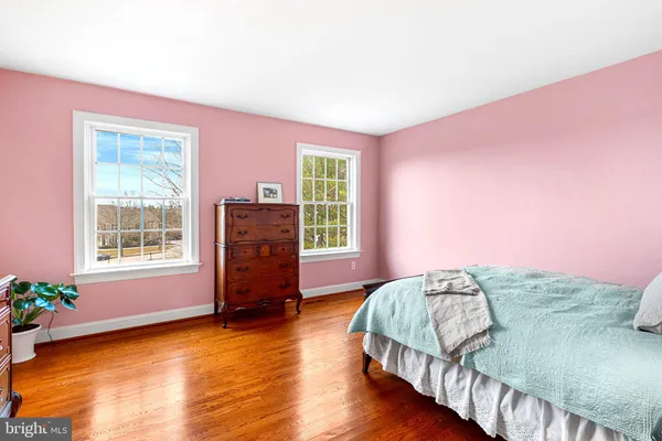 a spacious bedroom with a bed and wooden floor