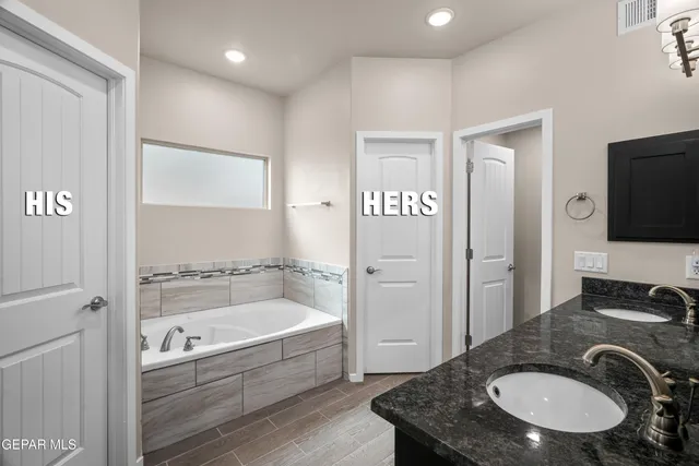 a bathroom with a granite countertop tub sink and mirror