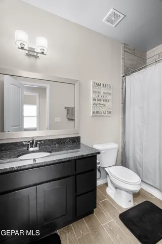 a bathroom with a granite countertop sink a toilet a mirror and shower