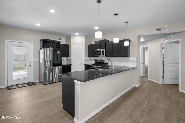 a large kitchen with kitchen island a large counter top a refrigerator and a sink