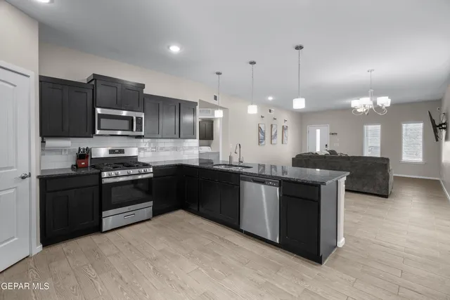 a kitchen with stainless steel appliances granite countertop a stove a sink dishwasher a refrigerator and a oven with wooden floor