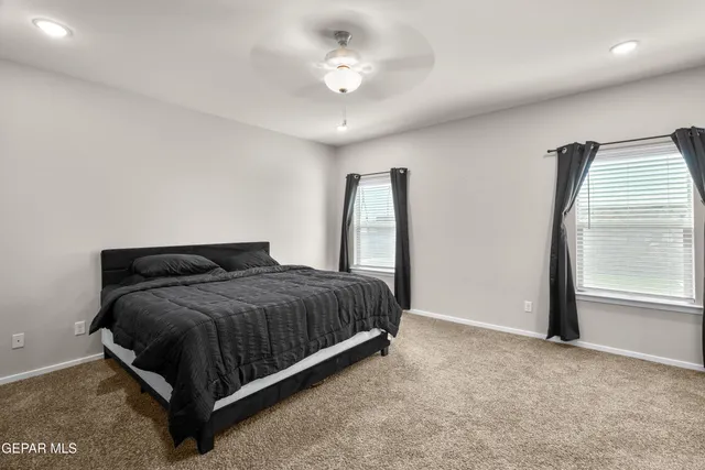 a spacious bedroom with a bed and a ceiling fan
