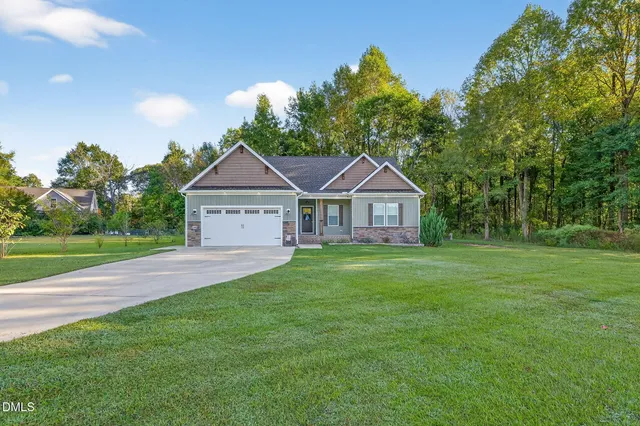 a front view of a house with a yard and trees