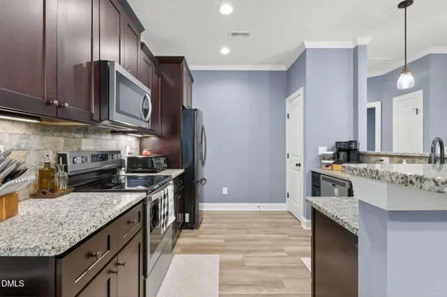 a kitchen with stainless steel appliances granite countertop wooden floors and sink