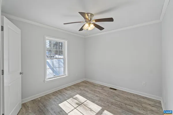 an empty room with wooden floor fan and windows