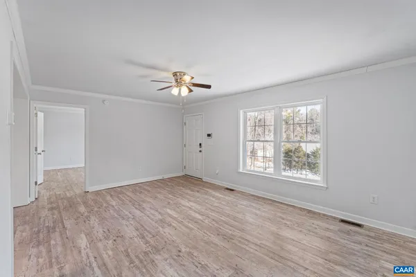 a view of an empty room with a window and wooden floor