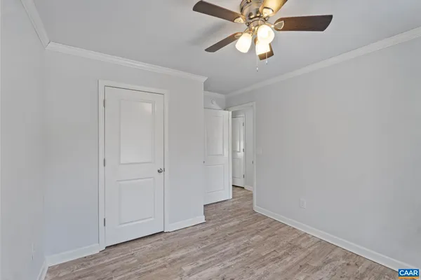 an empty room with wooden floor closet and fan
