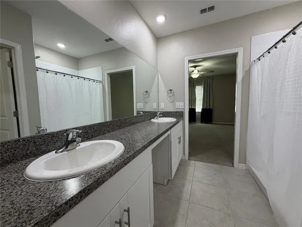 a en suite bathroom with a granite countertop sink and a mirror