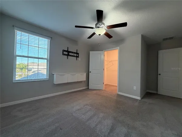 an empty room with windows and fan