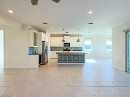 a room with stainless steel appliances kitchen island granite countertop a stove a sink a refrigerator a microwave and cabinets