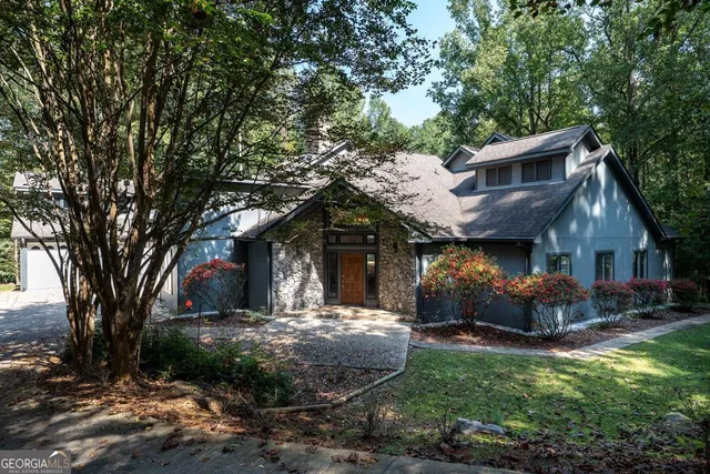 a front view of a house with a yard and large tree