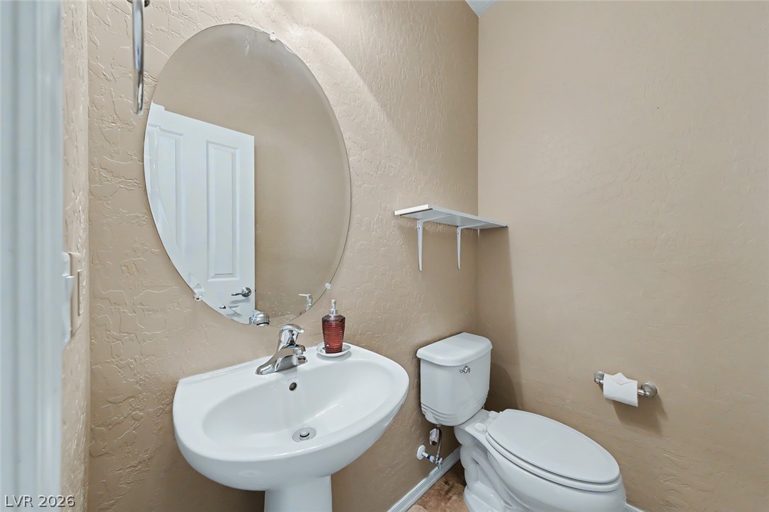 2356 Rue Bienville Way Henderson, NV 89044 - Photo 16 of 20 This bathroom features an oval mirror above the pedestal sink and toilet.