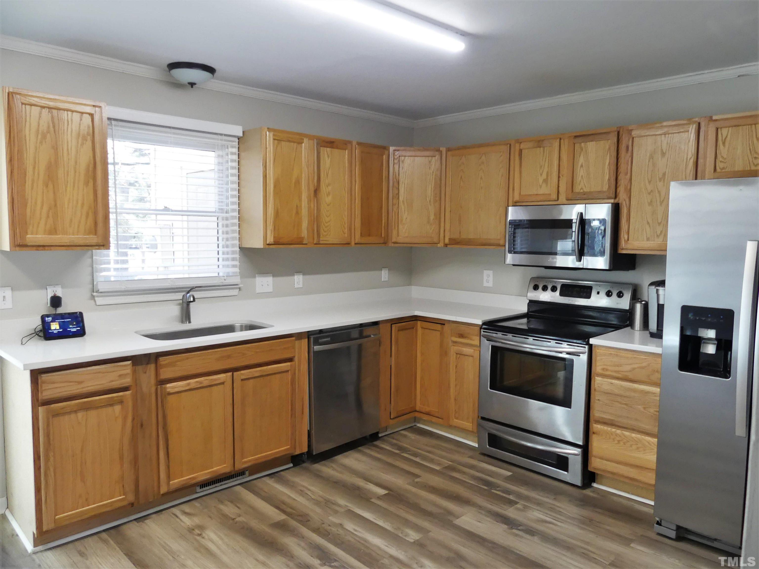 6520 English Oaks Drive Raleigh, NC 27615 - Photo 5 of 21 a kitchen with stainless steel appliances granite countertop a stove a sink dishwasher a microwave oven with cabinets and wooden floor