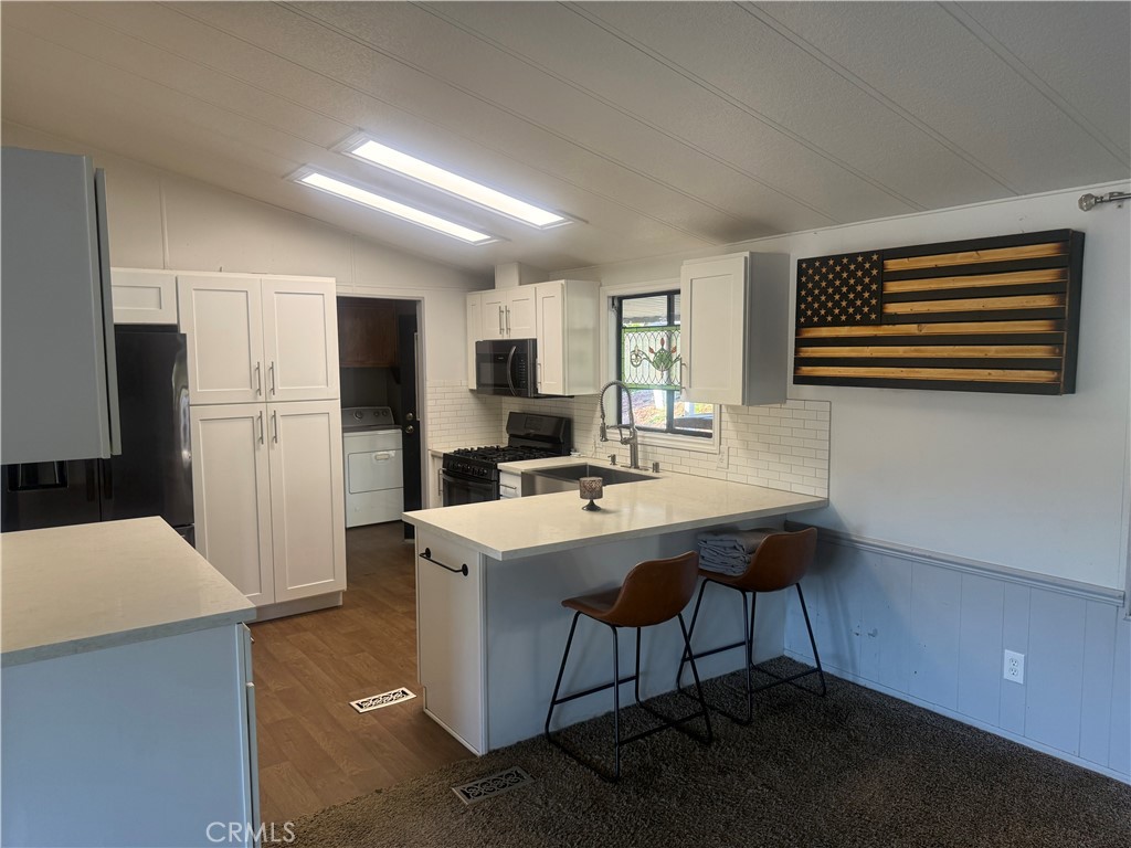 15181 Van Buren, Unit 256 Riverside, CA 92504 - Photo 10 of 34 a kitchen with a sink a refrigerator a microwave a island and chairs
