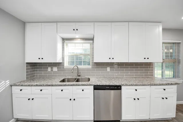 a kitchen with granite countertop white cabinets white appliances and a sink