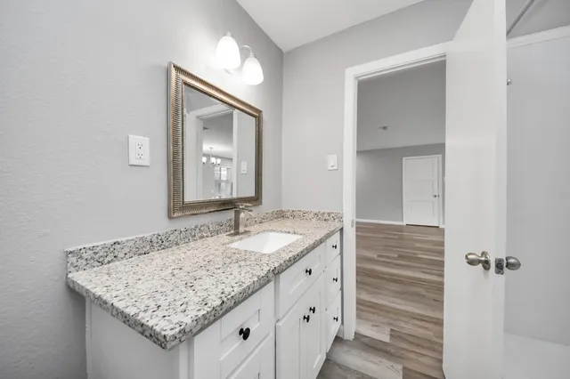 a bathroom with a granite countertop sink and a mirror