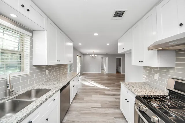 a large kitchen with stainless steel appliances granite countertop a sink and a stove