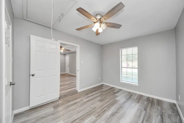 a view of an empty room with wooden floor and a window