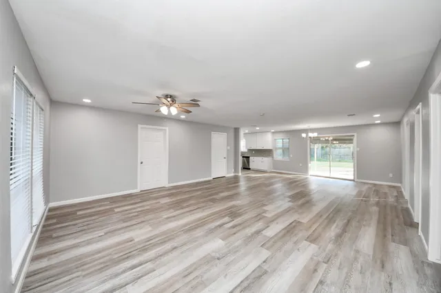 a view of empty room with wooden floor and fan