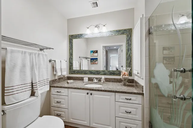 a bathroom with a granite countertop sink toilet a mirror a vanity and shower