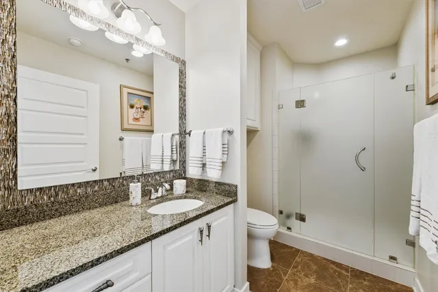 a bathroom with a granite countertop sink a toilet and shower