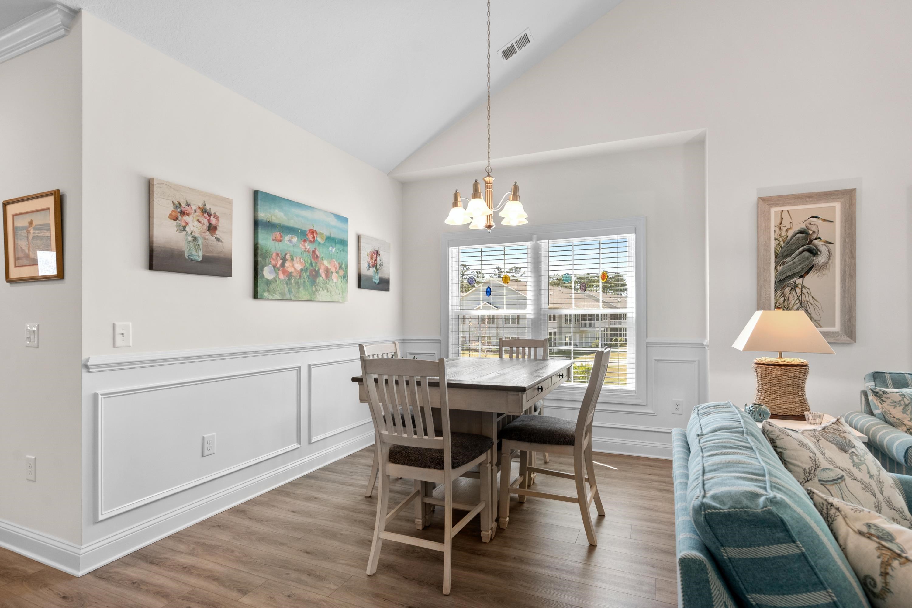 948 Jackline Place, Unit 201 Murrells Inlet, SC 29576 - Photo 12 of 37 Dining area featuring wood finished floors, wainscoting, high vaulted ceiling, a chandelier, and a decorative wall